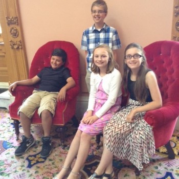 kids all smiling while sitting in chairs 